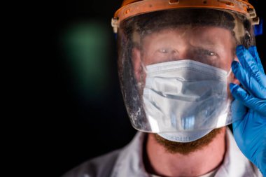 Avustralya 'da laboratuvar önlüğü ve eldiven giyerken maske ve yüz maskesi takan Covid doktor ve sağlık görevlisi..