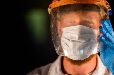 Avustralya 'da laboratuvar önlüğü ve eldiven giyerken maske ve yüz maskesi takan Covid doktor ve sağlık görevlisi..