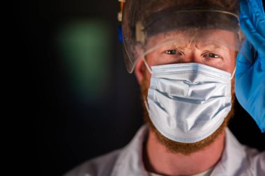 Avustralya 'da laboratuvar önlüğü ve eldiven giyerken maske ve yüz maskesi takan Covid doktor, hemşire ve sağlık görevlisi. Salgın sırasında hastaneye kaldırıldı..