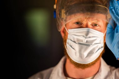 Avustralya 'da laboratuvar önlüğü ve eldiven giyerken maske ve yüz maskesi takan Covid doktor, hemşire ve sağlık görevlisi. Salgın sırasında hastaneye kaldırıldı..