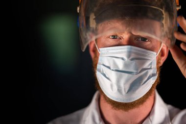 Avustralya 'da laboratuvar önlüğü ve eldiven giyerken maske ve yüz maskesi takan Covid doktor, hemşire ve sağlık görevlisi. Salgın sırasında hastaneye kaldırıldı..