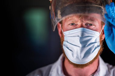Avustralya 'da laboratuvar önlüğü ve eldiven giyerken maske ve yüz maskesi takan Covid doktor, hemşire ve sağlık görevlisi. Salgın sırasında hastaneye kaldırıldı..