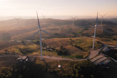 Rüzgar türbinleri tarlası ve gündoğumu. temiz enerji, çevre, elektrik ve sanayi kavramı