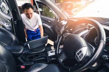 The technician analyzes the car's engine graph on the laptop computer in the garage. the concept of automotive, repairing, mechanical, vehicle and technology.