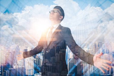 The double exposure image of the businessman standing during the sunrise overlays with the cityscape image. The concept of modern life, business, city life and internet of things.