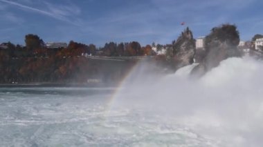 Rhine Falls, İsviçre - 24 Ekim 2020: Ren Şelalesi 'nde sonbahar, Avrupa' nın en büyük şelalesi. Turist teknesi şelalenin akan suyuna ve gökkuşağına çok yaklaşır..