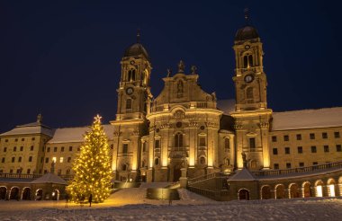 Einsiedeln 'deki Benedictine Manastırı, güçlü bazilikası ile İsviçre' deki ana Katolik hac merkezidir. Noel ağacı, karlı kış zamanı ve mavi saat