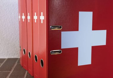 Zürih, İsviçre - 31 Aralık 2020: Ofis ortamında İsviçre bayrağının taklit edilmiş beyaz haçlı kırmızı klasörler