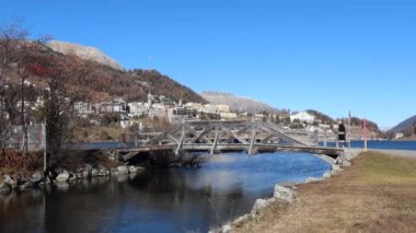St. Moritz, İsviçre - 26 Kasım 2020: St. Moritz İsviçre 'nin Engadine şehrinde yaklaşık 1800 metre yüksekliğinde bir Alp tatil köyüdür. Göldeki köprüden bir adam geliyor..