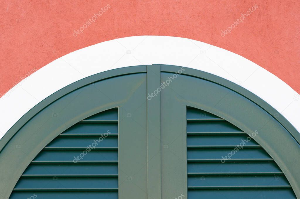 A detail of a window with closed green shutters on an old building in Morcote in swiss Ticino