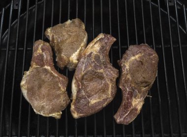 Gaz ızgarasında dört sulu, yarım kızarmış domuz pirzolası.