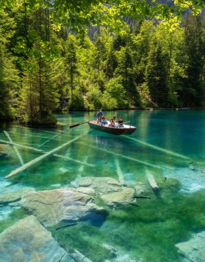 Blausee, İsviçre - 1 Haziran 2021: Blausee Gölü 'nde turist botu - İsviçre' nin Jungfrau bölgesinde Kandergrund 'un yukarısındaki Kander vadisinde bulunan mavi göl.