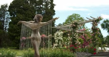 Almanya 'nın Insel Mainau adasındaki botanik bahçesinde bir kadın heykeli dalgalı bir bornozla sabit bir çekim.