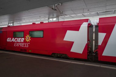 THUSIS, SWITZERLAND - APRIL 13, 2011: The glacier express from Zermatt to St.Moritz, panoramic train that crosses Alps. clipart