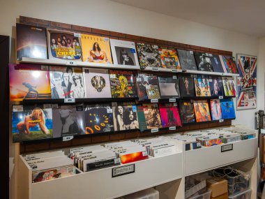 Bratislava, Slovakya - 21 Ekim 2025: Bir müzik mağazasında çeşitli albüm kapakları sergilenen vinil plakların duvar görüntüsü.
