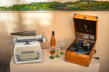 Mittelbergheim, Fransa - 6 Kasım 2025: Şarap şişesi ve gözlüklü klasik daktilo ve gramofon.