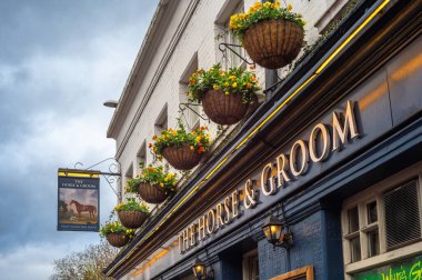 Londra, Birleşik Krallık - 24 Kasım 2025: Geleneksel İngiliz Barı Çiçek sepetleri asılmış At ve Damat.