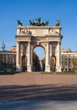 Milan, İtalya - 9 Aralık 2025: Mavi gökyüzünün altındaki bir şehir meydanında heykellerle birlikte Zafer Kemeri.