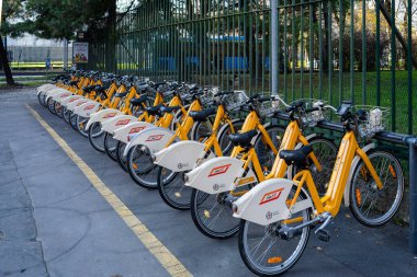 Milan, İtalya - 9 Aralık 2025: Şehir bisiklet paylaşım istasyonunda park edilmiş sarı renkli bisikletler.