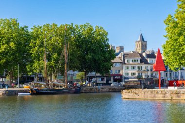 Caen, Fransa - 9 Ağustos 2025 Caen 'deki liman manzarası bir yelkenli, ağaçlar ve binalar.