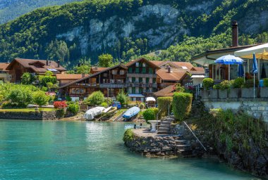 Iseltwald, İsviçre - 18 Temmuz 2025: Geleneksel ahşap evler ve teknelerle Iseltwald 'ın manzaralı göl köyü.