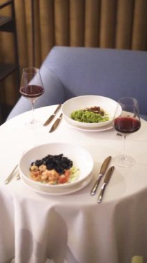 Garson bardağa şarap doldurur. Sıcak bir restoranda akşam yemeği. Dikey video