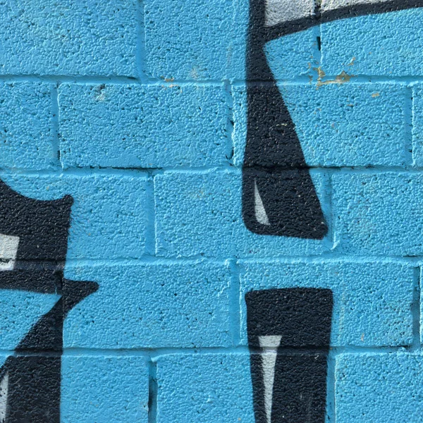 Parlak mavi tuğlalar boyama ve tabelayla desenlendirilmiş duvar. Canlı Şehir Duvarı Şablonu Arkaplanı. Yakın plan çek. Sokak Sanatı Konsepti.