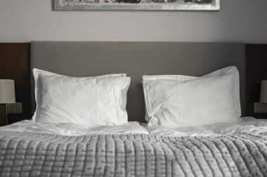 Yatakta iki beyaz pamuk yastık. Yorgan Battaniyesi ile rahat bir yatak odası. Seçici Odaklanma.