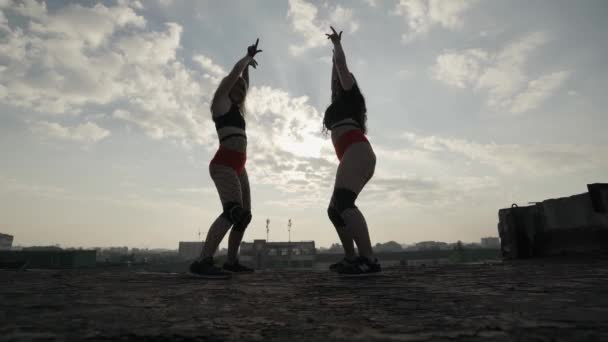 放棄された建物の屋根の上で2人の女の子が踊ります。女の子で赤ショートパンツと小切手. — ストック動画