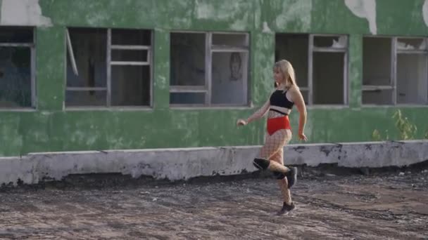 Dos chicas se encuentran en el techo de un edificio abandonado y comienzan a bailar twerk. Chicas en pantalones cortos rojos y medias a cuadros. — Vídeo de stock