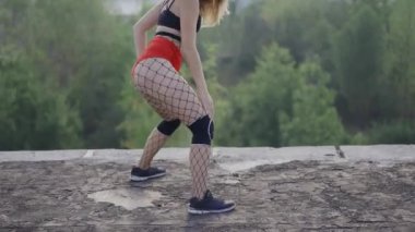 Kız terk edilmiş bir binanın çatısında twerk dansı yapıyor. Kırmızı şortlu ve taytlı bir kız hücrede..
