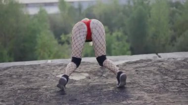 Kız terk edilmiş bir binanın çatısında twerk dansı yapıyor. Kırmızı şortlu ve taytlı bir kız hücrede..