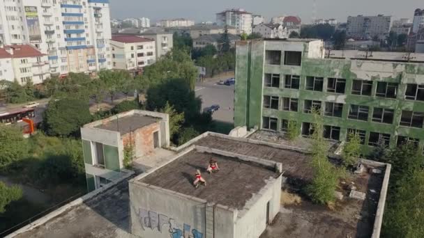 Twee meisjes dansen twerk op het dak van een verlaten gebouw. Meisjes in rode shorts en geruite maillot. vanuit de lucht bekeken — Stockvideo