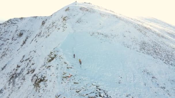 Tres viajeros descienden de la montaña. Baja por un camino empinado entre las piedras. Vista aérea. — Vídeos de Stock