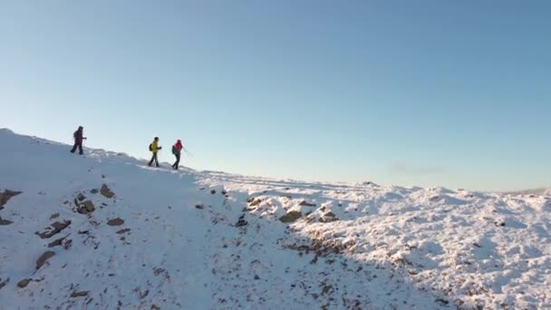Три мандрівники спускаються з гори. Сніжні вершини зимових Карпат. Вид з повітря . — стокове відео