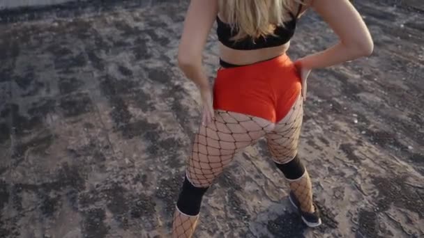 Girl dances twerk on the roof of an abandoned building. Girl in red shorts and tights in a cell. — Stock Video