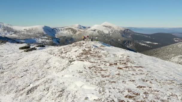 Os viajantes ficam no topo de uma montanha nevada. Vista aérea do panorama da montanha. — Vídeo de Stock
