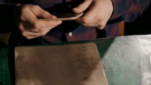 Le processus de fabrication d'un portefeuille en cuir fait main. L'artisan se prépare à envelopper un sac à main. Maroquinerie artisanale. — Video