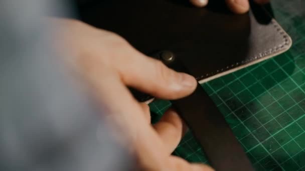 Le processus de fabrication d'un portefeuille en cuir fait main. L'artisan combine des éléments avec des rivets. Maroquinerie artisanale. Macro. — Video