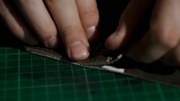 The process of manufacturing a leather wallet handmade. The artisan puts glue on the leather parts of the wallet and glued them. Handmade leather goods. Macro . — Stock Video