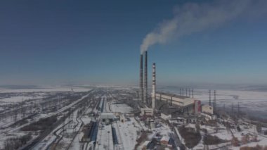 Kömür santralinden gelen gri dumanlı yüksek baca borularının havadan görüntüsü. Fosil yakıtla elektrik üretimi.