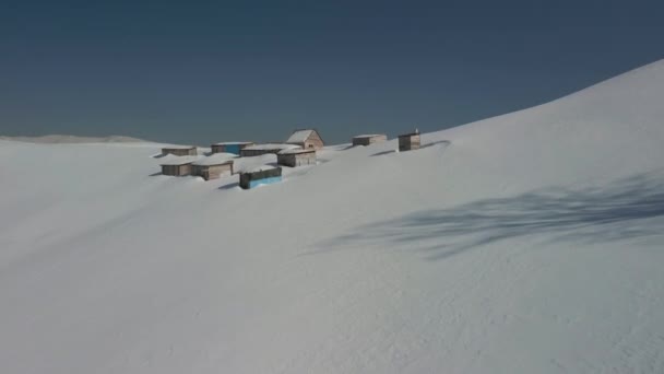 Flygfoto över en alpin bosättning på en bakgrund av snötäckta vinterberg. Ukraina Karpaterna. — Stockvideo