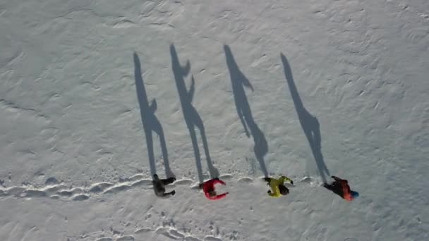 Grote schaduwen in de sneeuw van vier reizigers. Luchtfoto van mensen die op diepe sneeuw lopen en grote schaduw geven. — Stockvideo