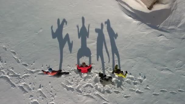 Вид з повітря на чотири великі тіні в снігу. Мандрівники танцюють і показують різні кумедні фігури, що відображають велику тінь на білому снігу . — стокове відео