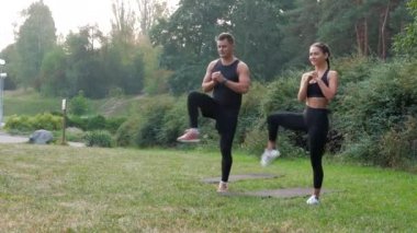 Dışarıda parkta iki koşucu esneme egzersizi yapıyor. Sabah iki koşucu ısınma egzersizi. Uygun çift antrenman bacakları. Bacaklarını esneten kaslar. Erkek ve kadın bacaklarını açıyor.