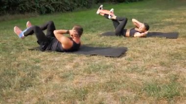 Açık havada birkaç çatırtı egzersizi. Spor çifti egzersiz yapıyor. Sağlıklı bir antrenman. Erkek ve kadın karın kaslarını çalıştırıyor. Formda insanlar antrenman yapıyor. Antrenman eğitimi
