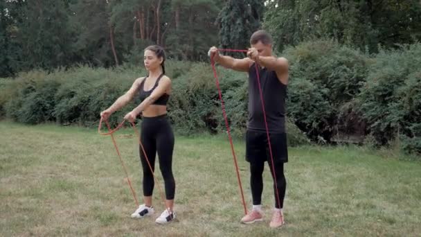 适合夫妇做抵抗带运动 带阻力带的夫妇锻炼 男人和女人在室外与体育乐队一起训练 适合的人锻炼生活方式 两名运动员一起热身 — 图库视频影像