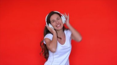 Müzik kulaklıklarıyla milenyum dansı. Kırmızı stüdyoda müzik dinleyen bir kadın. Kulaklıkla dans eden mutlu bir model. Havalı kız kulaklık söylüyor. Mutlu model şarkı listesi. Kız öğrenci müzikle dans ediyor.