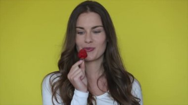 Neşeli kadın çilek yer. Seksi kadın sarı stüdyoda çilek yiyor. Güzel bir kız sağlıklı meyvelerden zevk alır. Kırmızı böğürtlen tutan mutlu kadının portresi. Erotik model tatlı çilek tadı