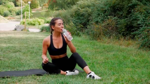 健康的女人在户外运动后喝水 健康的运动员在训练后喝水 体育运动者把瓶装水放在大自然中 女性健康福利 — 图库视频影像